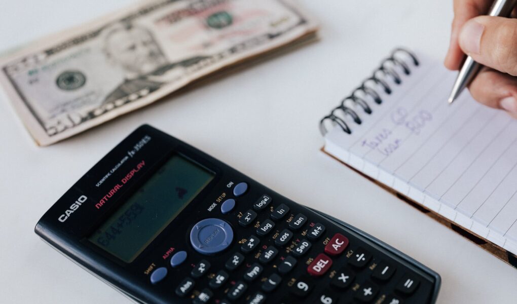 crop unrecognizable accountant counting savings using notebook and calculator