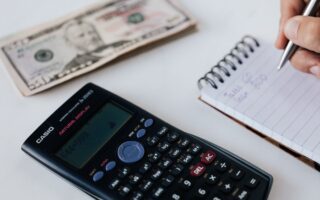 crop unrecognizable accountant counting savings using notebook and calculator